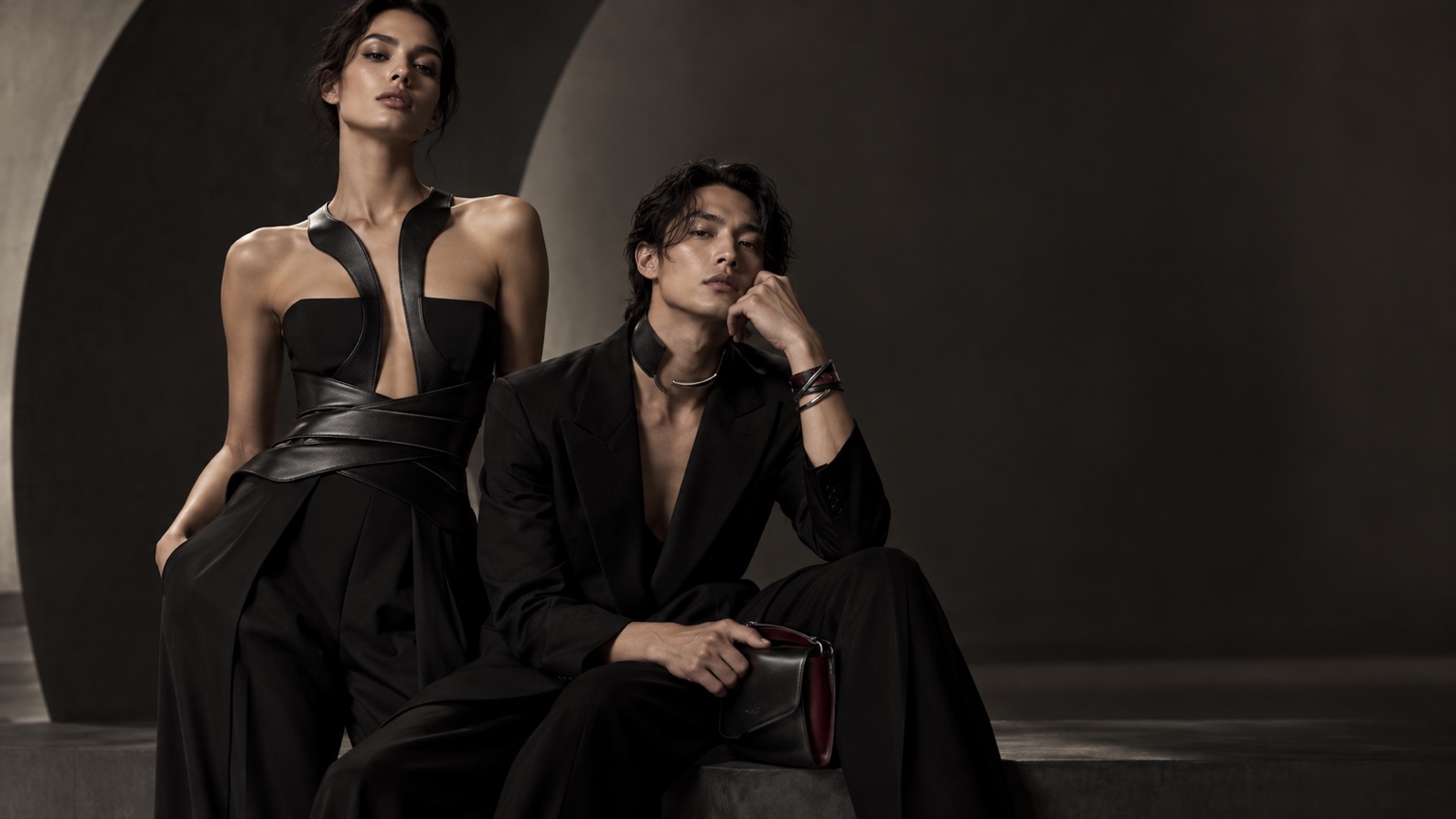 Two models wearing black Second Skin pieces in a dark architectural setting